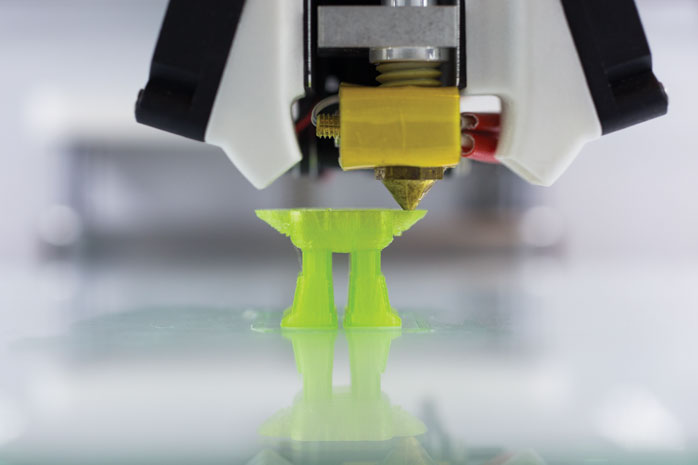 Figure 5 — 5 — An FDM printer mid-print, laying down a part layer by layer — how every DFCD chassis component is produced. Photo via web search (personal-reference use).