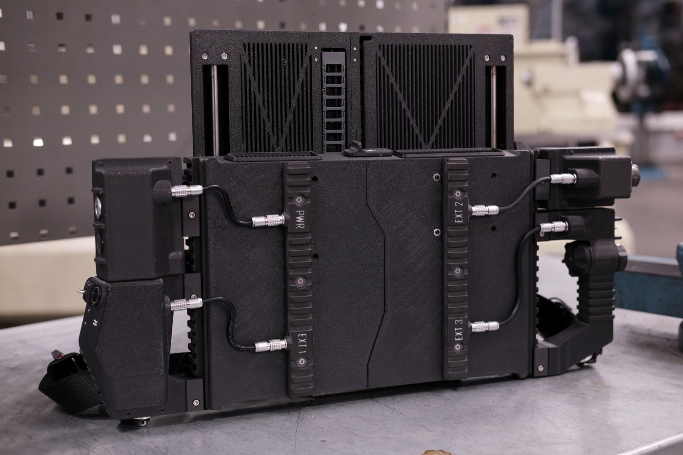 Figure 5 — 5 — The assembled DFCD's rear face, showing the PWR/EXT1–EXT3 rail sockets, the 0B self-locking connectors linking the side modules to the rails, and the strap-clip hardware at the lower-l…